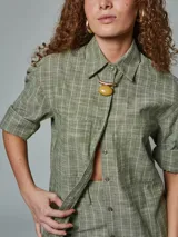 Camisa de manga larga color ladrillo con rayas blancas, confeccionada en lino. Tiene cuello clásico, cierre frontal con botones y bolsillo de parche en el pecho.