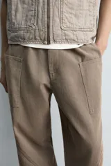 Pantalón cargo de algodón color marrón con efecto lavado, corte relajado y tiro medio. Presenta cintura elástica con botón y cierre de cremallera, bolsillos delanteros, bolsillos plastrón en la espalda y grandes bolsillos cargo en las perneras.