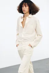Camisa color crema de algodón y lyocell, con cuello solapa, manga larga con puños y bolsillo de parche en el pecho.