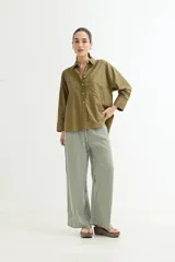 Camisa de manga larga, color verde oliva, con cuello camisero y botones frontales. Presenta un bolsillo de parche en el pecho y un corte holgado.