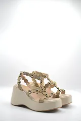 Sandalias color beige con plataforma y tiras decoradas con esferas doradas.