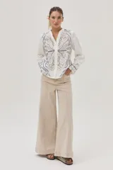 Camisa blanca de lino con bordados florales en tonos beige y azul.