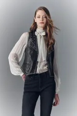 Chaleco negro de cuero ovino con tachas metálicas, botones al frente, bolsillos ojal y tira de ajuste en la espalda.