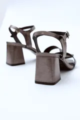 Sandalias de cuero charol negro con tira delgada sobre los dedos, pulsera con hebilla al tobillo y tacón cuadrado.