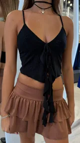 Top negro brillante con tirantes finos, escote en V y volados frontales.