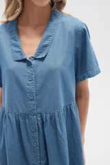 Vestido corto camisero de denim celeste, con cuello camisero, mangas cortas y falda acampanada con botones frontales.