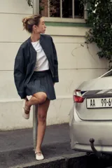 Cazadora bomber de denim color gris oscuro, con cuello redondo, cierre frontal con cremallera metálica, bolsillos laterales y mangas largas con puños elásticos.