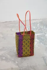 Bolso tipo tote tejido con tiras de plástico de colores amarillo, morado, naranja y negro.