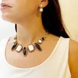 Collar de bronce con piedras naturales engarzadas. Presenta piedras rectangulares blancas nacaradas y piedras ovaladas negras, todas con bordes dorados texturizados.