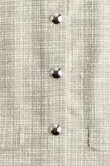 Saco corto de tweed color beige, con cuello redondo, cierre frontal con botones dorados y bolsillos delanteros decorativos.