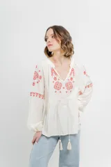 Blusa color crema de gasa liviana con bordado artesanal rojo en delantero y mangas. Escote en V con cordones y borlas. Mangas largas con puño elástico.