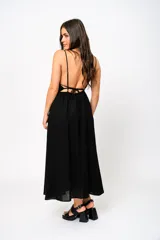 Vestido largo negro con escote en V, tirantes finos y espalda baja. Tiene frunces en la cintura que realzan la silueta.