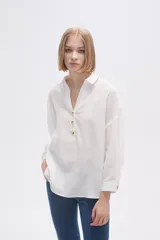 Blusa blanca holgada de poliéster con cuello camisero y mangas largas.