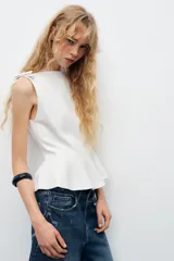 Top color lila de cuello barco y sin mangas, con detalle de lazos en los hombros y corte peplum en la cintura.