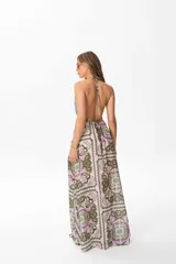 Vestido largo con estampado abstracto en tonos verdes y violetas, escote halter pronunciado y espalda descubierta.