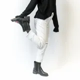 Bota Chelsea blanca de cuero sintético con elástico lateral negro adornado con tachas plateadas. Tiene suela track negra y taco bajo.