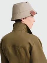 Sombrero tipo bucket reversible, negro de un lado y beige del otro, con detalle de cuero marrón con botón metálico en el lateral.