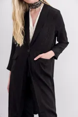 Kimono largo hasta la rodilla, color negro con estampado jacquard. Tiene solapa, botón frontal, tajos laterales y bolsillos ojal con solapa en el frente.