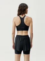 Top deportivo negro de alta sujeción, con corte atlético y pieza en curva para ajuste perfecto. Interior de tejido mesh para mayor ligereza y copas extraíbles.