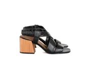 Sandalias negras de cuero con tiras cruzadas y talón elástico fruncido. Taco de madera de 7,5 cm y punta cuadrada.