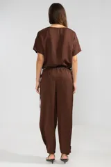 Pantalón de trabajo color marrón chocolate, confeccionado en lino y tencel. Presenta corte holgado, bolsillos laterales, cintura elástica con cordón ajustable y detalle regulable en el tobillo.