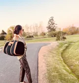 Bolso de viaje grande de cuero vacuno color negro con detalles en marrón. Tiene herrajes metálicos, gran superficie interna, asa de mano y correa para el hombro.