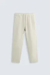 Pantalón color arena de corte recto, confeccionado en tejido de algodón y lino. Cuenta con cintura elástica ajustable con cordón, bolsillos delanteros y traseros de parche.