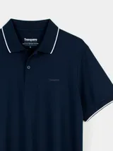 Remera tipo polo color beige, de corte clásico, con cuello y puños acanalados en contraste marrón oscuro.