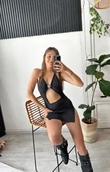 Minivestido negro con escote halter, abertura en el abdomen y tajo lateral.