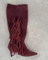 Bota alta de cuero color borgoña con taco fino y detalle de flecos en el lateral.