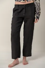 Pantalón de lino blanco, de corte recto y tiro medio, con bolsillos laterales y cierre frontal con botón y cremallera.