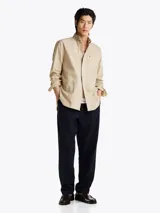 Camisa beige de corte amplio confeccionada en sarga de puro algodón teñido en prenda. Tiene cuello con botones, bolsillo de parche en el pecho y puños redondeados con botón.