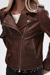Chaqueta marrón de eco-cuero, corte recto, con cierre asimétrico y cuello solapa.