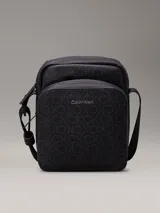 Cartera tipo bandolera de piel sintética en color negro, con monograma estampado y logo de Calvin Klein.
