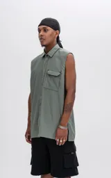 Camisa sin mangas color verde militar de calce oversize con doble bolsillo y detalle de remaches en el frente, confeccionada en tejido twill.