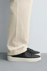 Zapatillas deportivas blancas de caña baja con detalle de color gris en el talón y suela con volumen.