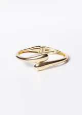 Pulsera brazalete rígido dorado con terminaciones redondeadas y cierre con bisagra.
