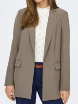 Blazer largo color marrón topo, de corte holgado y tejido sastrero con trama twill. Tiene cuello con solapa y bolsillos delanteros funcionales.