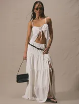 Pollera larga blanca de tiro alto, con volados en capas y abertura lateral ajustable con cordones.