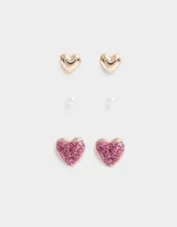 Set de tres pares de aros pasantes con forma de corazón: un par dorado, un par con perlas y un par con glitter rosa.