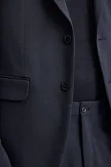 Blazer slim fit azul marino confeccionada en tejido con 17% de lana. Cuello con solapas de muesca, manga larga acabada en puño con detalle de botones, bolsillo de vivo en pecho y de solapa en cadera, detalle bolsillo interior, bajo con aberturas en espalda y cierre frontal con botones.