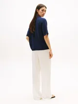 Sweater azul marino de tejido de punto, con cuello en V con ribete de rayas rojas y blancas, mangas cortas y logo bordado en el pecho.