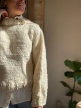 Sweater tejido de lana merino color crudo, con cuello alto y mangas largas abullonadas. Tejido artesanal con punto grueso.