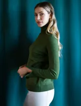 Polera de punto fino marca Nienty, color blanco, con cuello alto volcado y mangas largas con detalle de tajo en los puños.