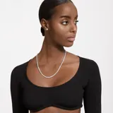 Conjunto de collar y aros plateados con circonitas blancas. El collar es una cadena integral de piedras brillantes y los aros son pequeños botones.