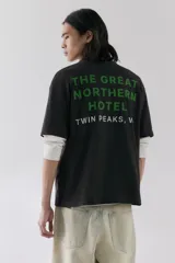 Remera negra de corte holgado y mangas cortas, con cuello redondo y estampado pequeño de llave de hotel en el pecho.
