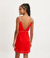 Vestido corto rojo de lino con tirantes dobles y costuras en contraste. Tiene una abertura debajo del busto y pespuntes vistos en el ruedo.