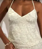 Top blanco con breteles finos y escote en V, con bordado de flores en relieve.