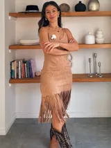 Vestido color beige con breteles finos, corte ajustado y falda con flecos.