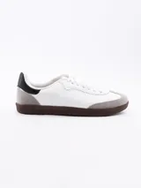 Zapatillas urbanas negras con cordones blancos y suela marrón.